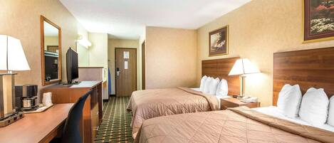 A hotel room with two beds, a desk with a computer, a TV, and a mirror.