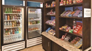 A convenience store with refrigerated beverage coolers, snack shelves, and a 'Suite Shop' sign.