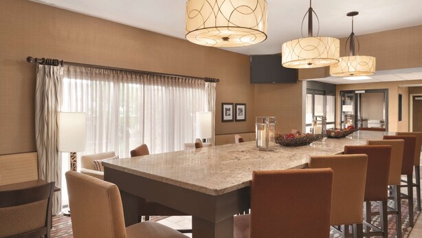 A dining area with a large table, multiple chairs, and pendant lighting.
