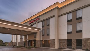 A modern hotel entrance with a covered parking area and a sign reading "Hampton Inn."