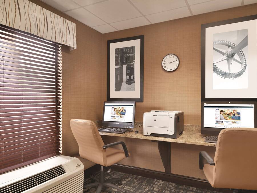 Un'area reception di un hotel con due postazioni computer, un orologio e opere d'arte incorniciate appese al muro.
