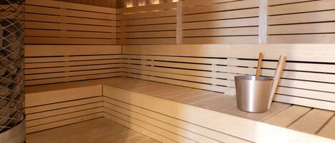 A sauna with wooden slats, a bench, and a metal bucket with a wooden stick.