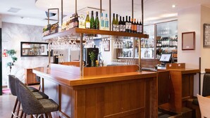 A bar area with a wooden counter, multiple wine bottles, and a variety of glasses. - Scandic Helsinki Aviapolis (Vantaa)