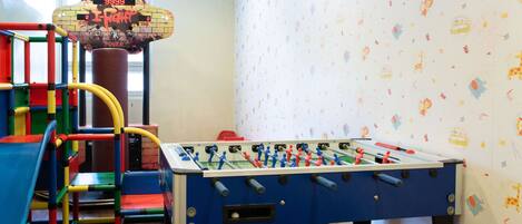 A play area with a foosball table, colorful play structures, and a life score display.