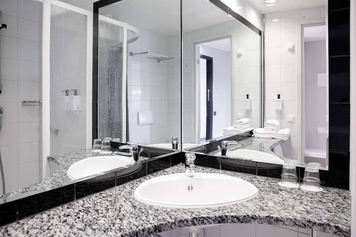 Un baño moderno con dos lavamanos, un espejo grande y zona de ducha.