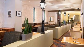 Een hotel lobby met zithoeken, tafels en decoratieve planten.