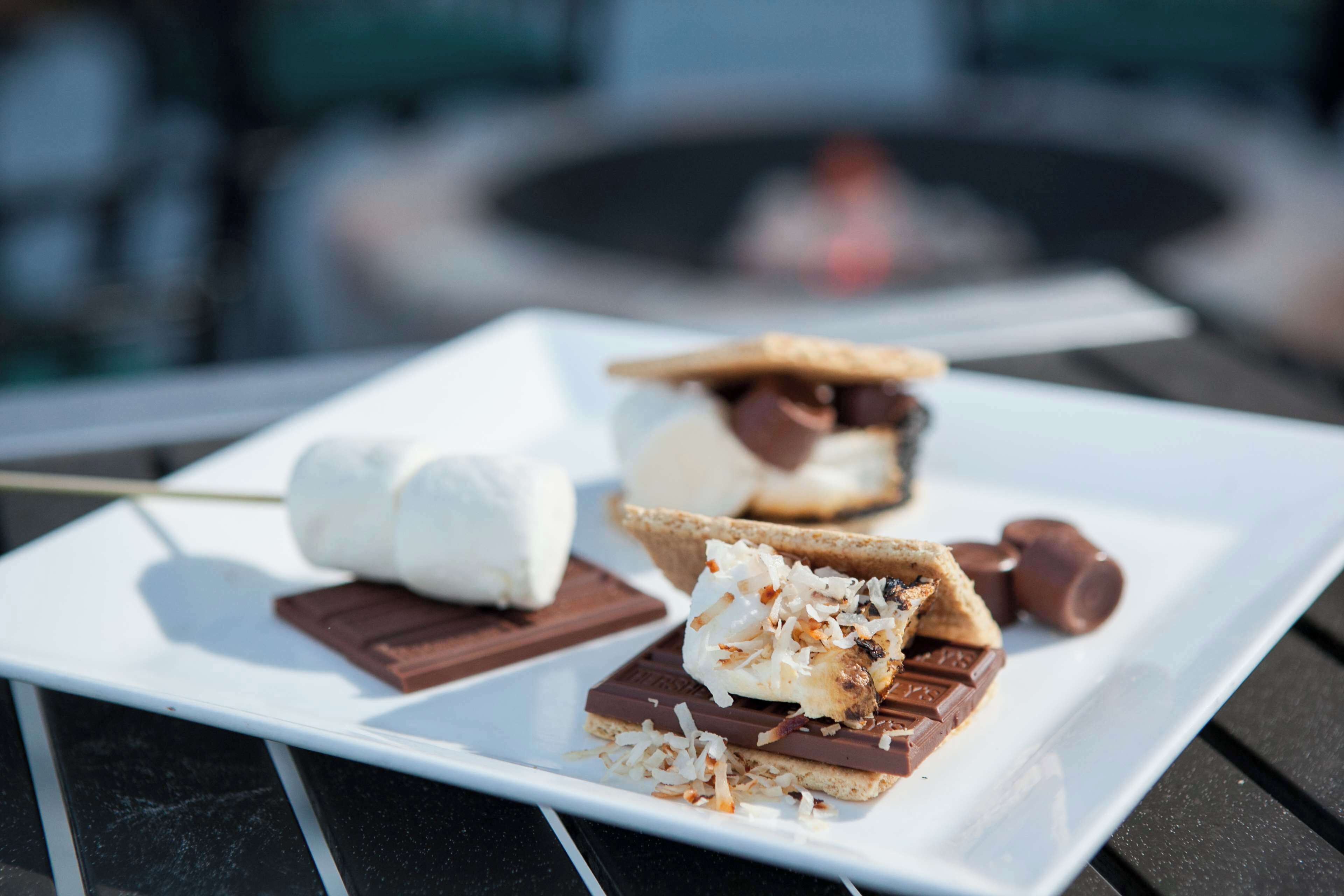A dessert plate with marshmallows, chocolate, and graham crackers on a white plate.