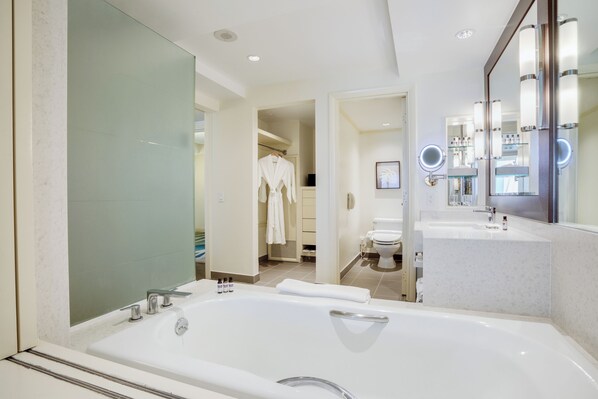Un baño moderno con una bañera grande, un tocador con espejo y un vestidor.