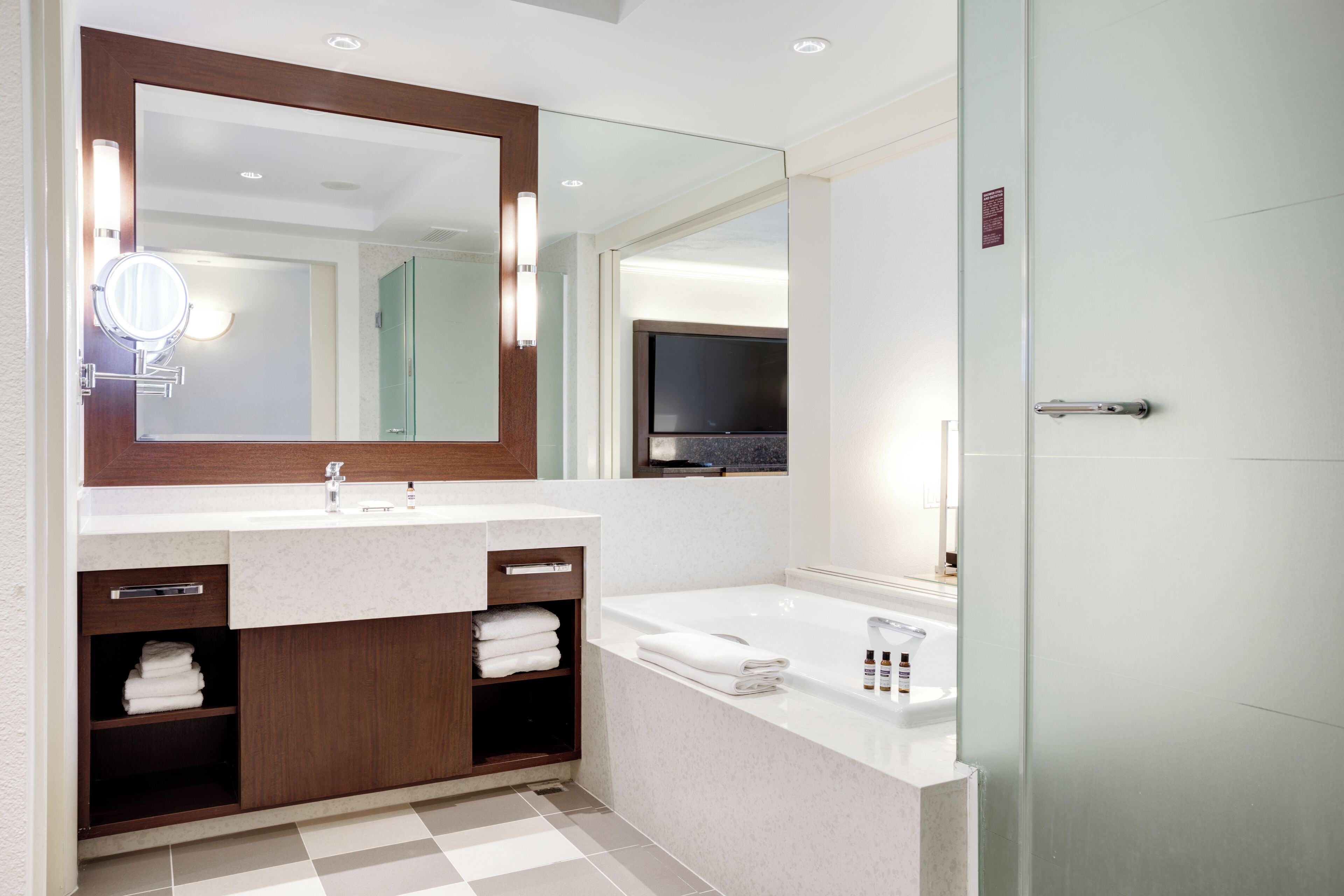 A modern bathroom with a double sink vanity, a large mirror, and a bathtub.
