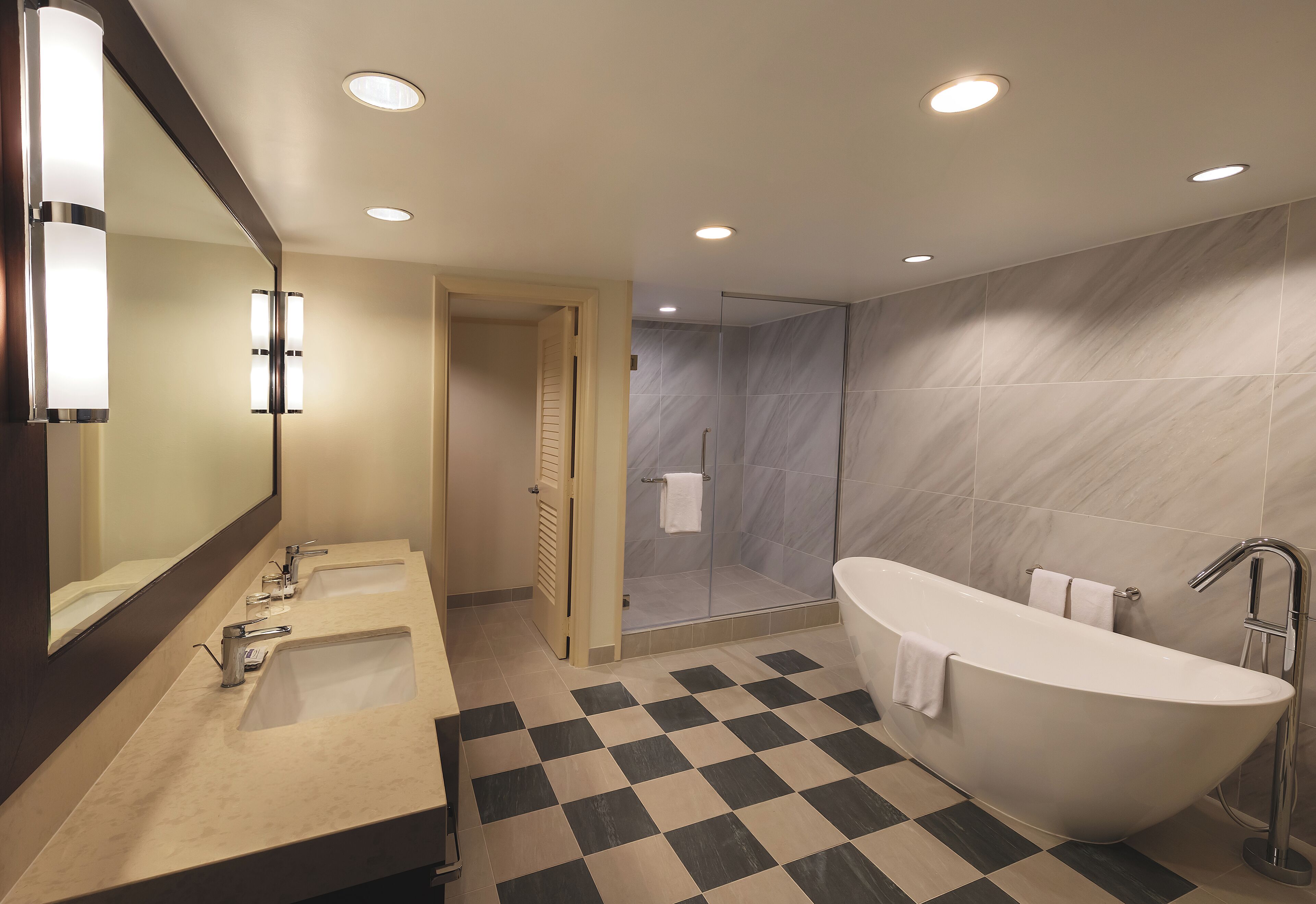 Un baño moderno con dos lavamanos, ducha y bañera independiente.