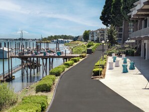 A waterfront walkway with a marina, a bridge, and buildings with balconies. - Holiday Inn Portland - Columbia Riverfront by IHG (Portland)