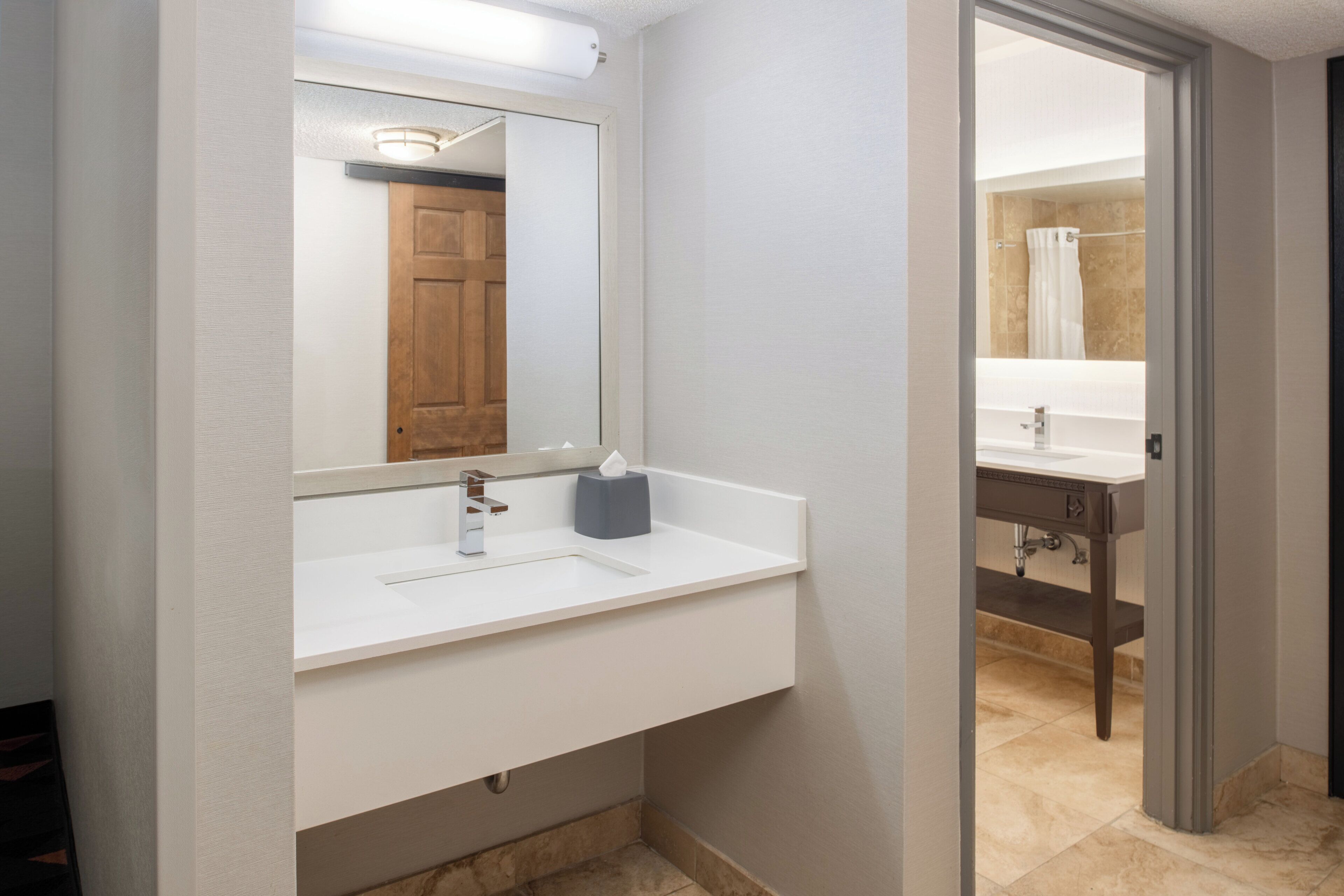 A bathroom with a white sink, a mirror, and a wooden door.