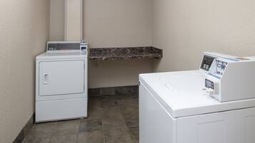 A laundry area with two white washing machines and a marble countertop.
