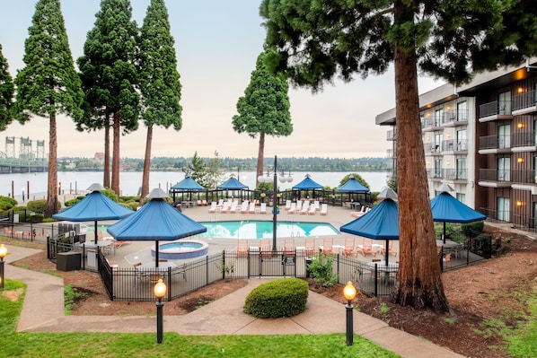 Una piscina al aire libre, sombrillas, sillones reclinables de piscina