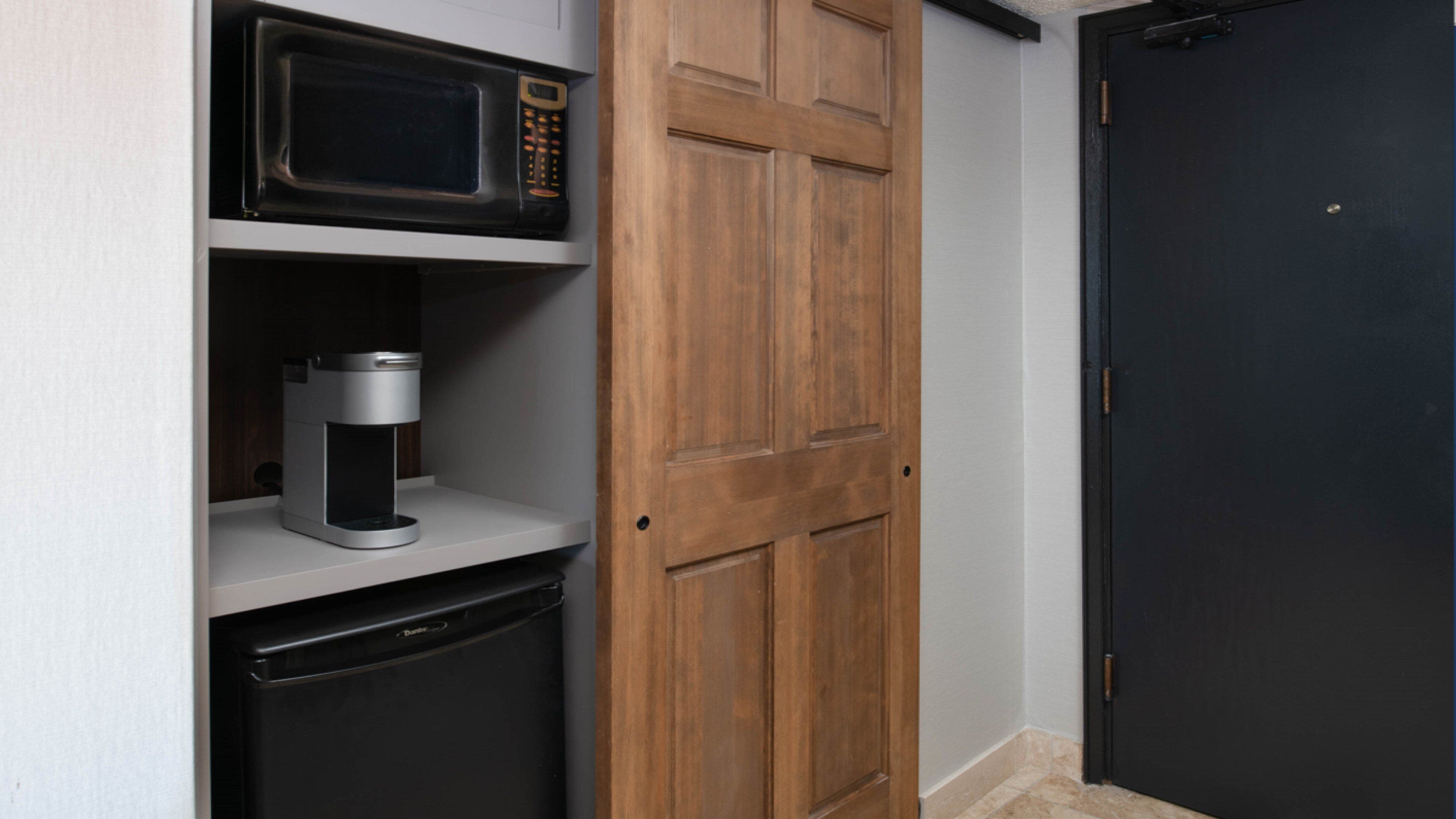 A compact kitchenette with a microwave, coffee maker, and dishwasher.