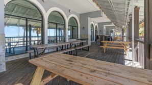 A covered outdoor dining area with wooden benches and tables, large arched windows, and a view of the beach. - Sun N Sand Resort (Myrtle Beach)