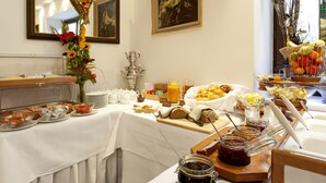 A breakfast buffet with various food items, a heart-shaped flower arrangement, and a rooster painting on the wall. - Hahn Hotel (Munich)