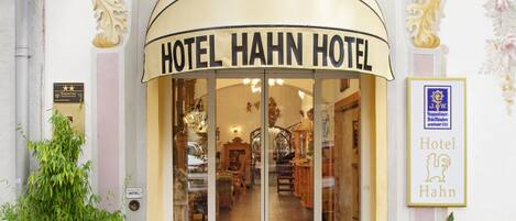 The entrance of Hotel Hahn Hotel with a classic facade, a prominent entrance, and a sign indicating the hotel's name.