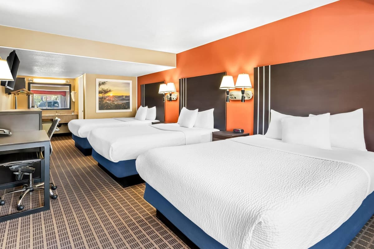 Ein Hotelzimmer mit zwei Betten, einem Schreibtisch und einem Stuhl.
