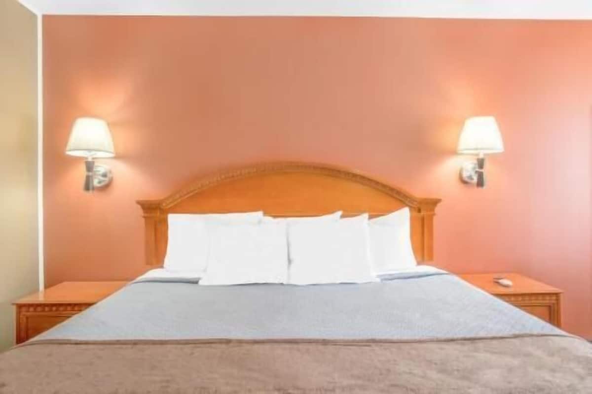 Ein Hotelzimmer mit einem Bett, zwei Nachttischlampen und einem hölzernen Kopfteil.