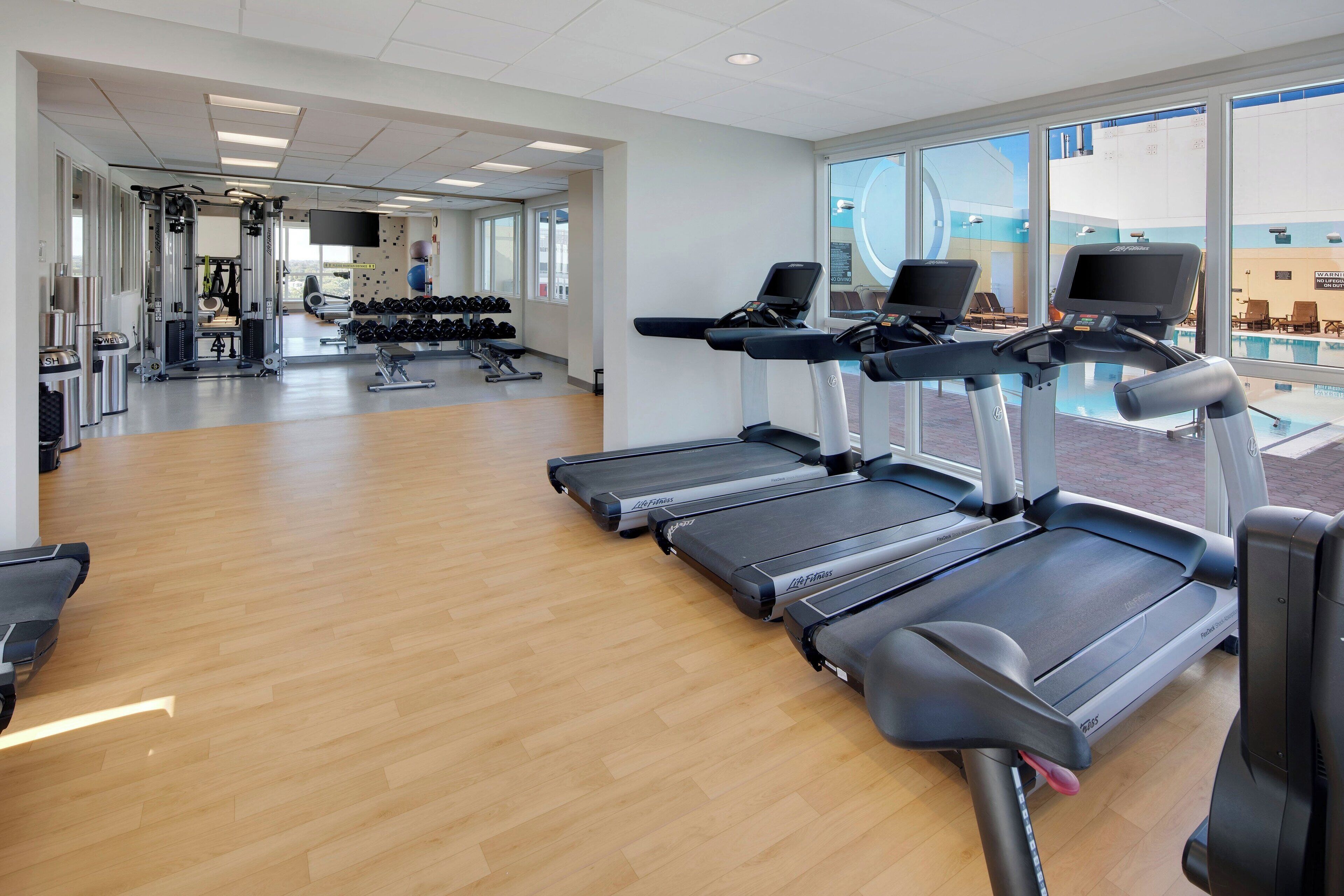 Ein Fitnessstudio mit Laufbändern, Kurzhanteln und Trainingsgeräten.