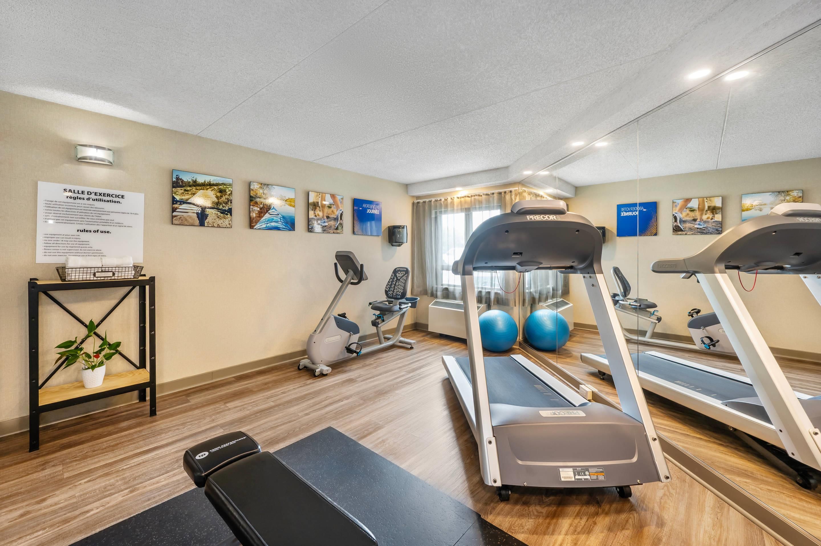 A fitness room with treadmills, exercise bikes, and a wall-mounted mirror.