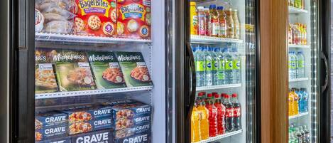 Une vitrine réfrigérée dans un magasin, où sont exposés divers produits alimentaires et boissons.