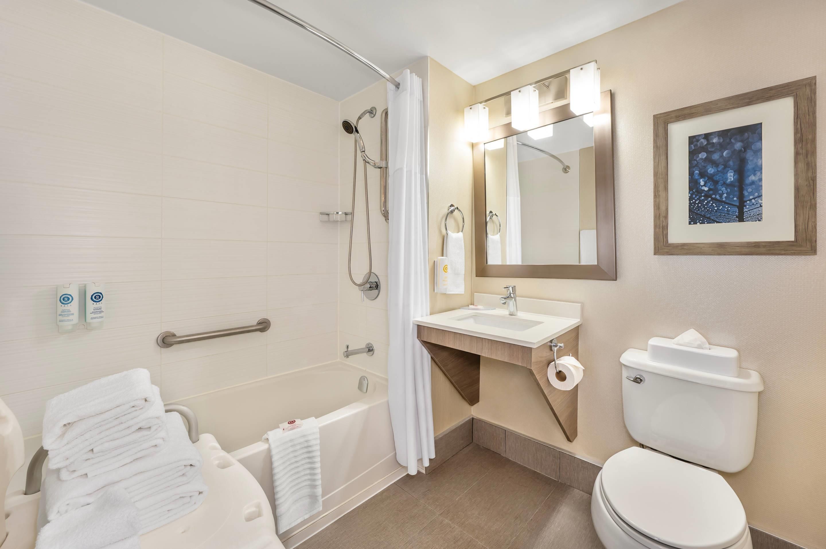 A modern bathroom with a bathtub, shower, toilet, and sink.