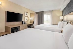 A hotel room with two beds, a flat-screen TV, a desk with a lamp, and a window with curtains. - Comfort Inn Aéroport (Dorval)