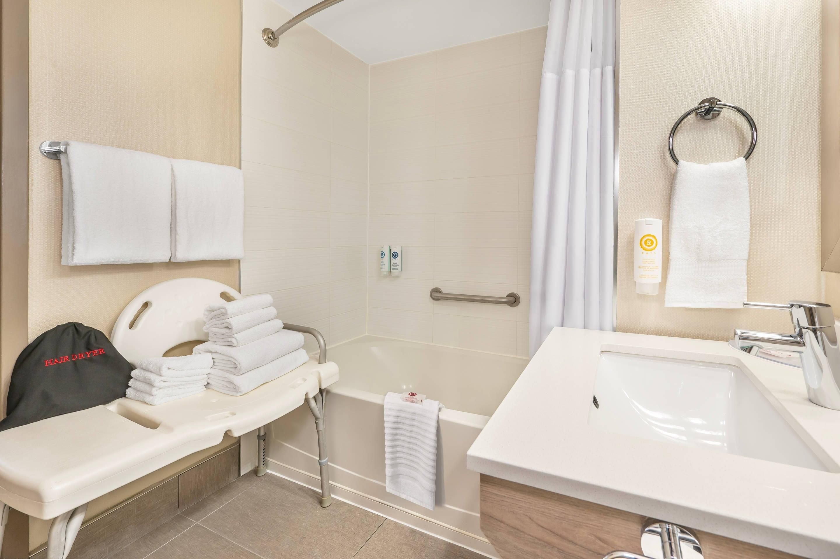 A bathroom with a shower, a sink, and a hair dryer.
