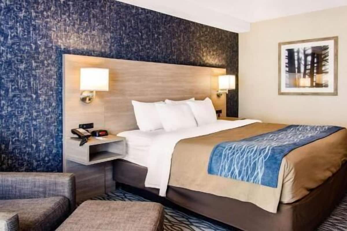 Habitación de hotel con cama, mesitas de noche, una silla y una pared con textura.