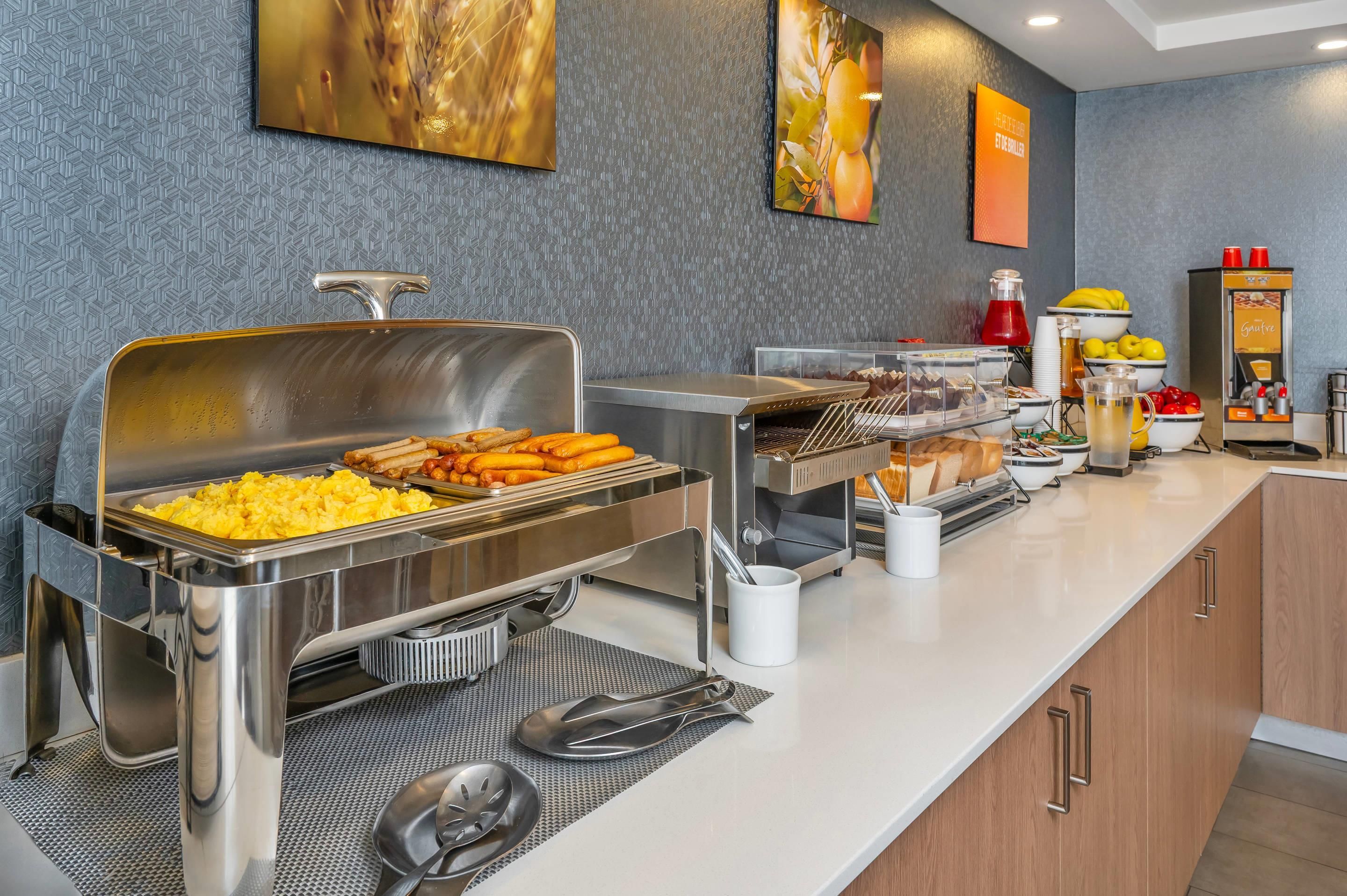 A buffet setup with various food items, a beverage dispenser, and a coffee machine.
