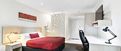 Una habitación de hotel moderna con cama, mesita de noche, escritorio, silla y televisor.