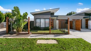 A modern house with a fenced backyard, a garage, and a well-maintained lawn. - The Aspen & Apartments (Sale)