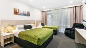 A hotel room with two beds, a desk, a chair, and a painting on the wall. - The Aspen & Apartments (Sale)