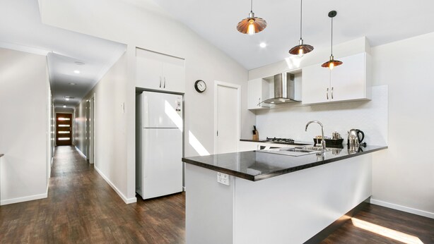 A modern kitchen with white cabinetry, a black countertop island, and pendant lighting. - The Aspen & Apartments (Sale)
