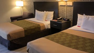 A hotel room with two beds, each with a headboard, bedside tables, lamps, and a nightstand.