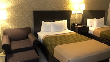 A hotel room with two beds, a sofa, and a nightstand with a lamp.