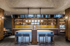 A modern bar area with a central island and multiple bar stools. - Crowne Plaza London - Kings Cross by IHG (London)