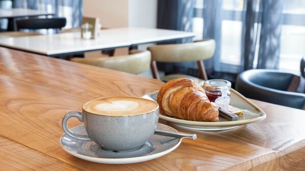 A table with a cup of coffee and a croissant on a tray. - Crowne Plaza London - Kings Cross by IHG (London)
