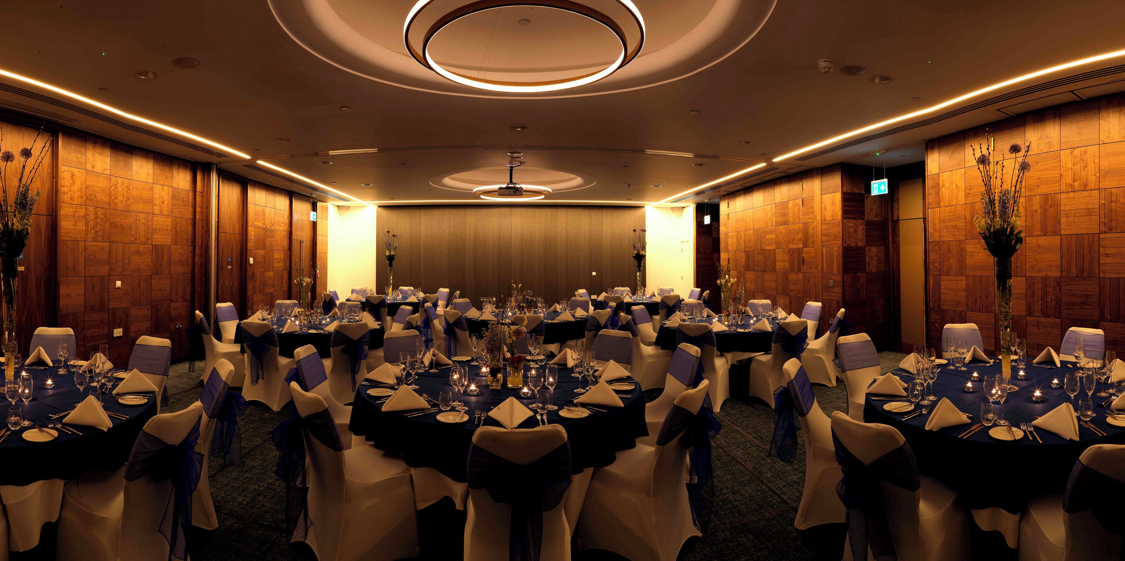 A conference room with round tables, chairs, and a chandelier.