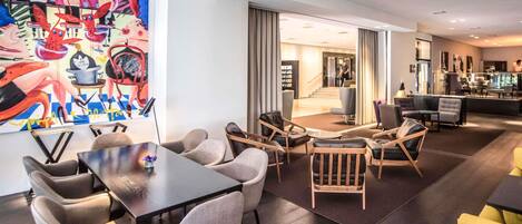 A modern hotel lobby with a dining area, a staircase, and a bar.