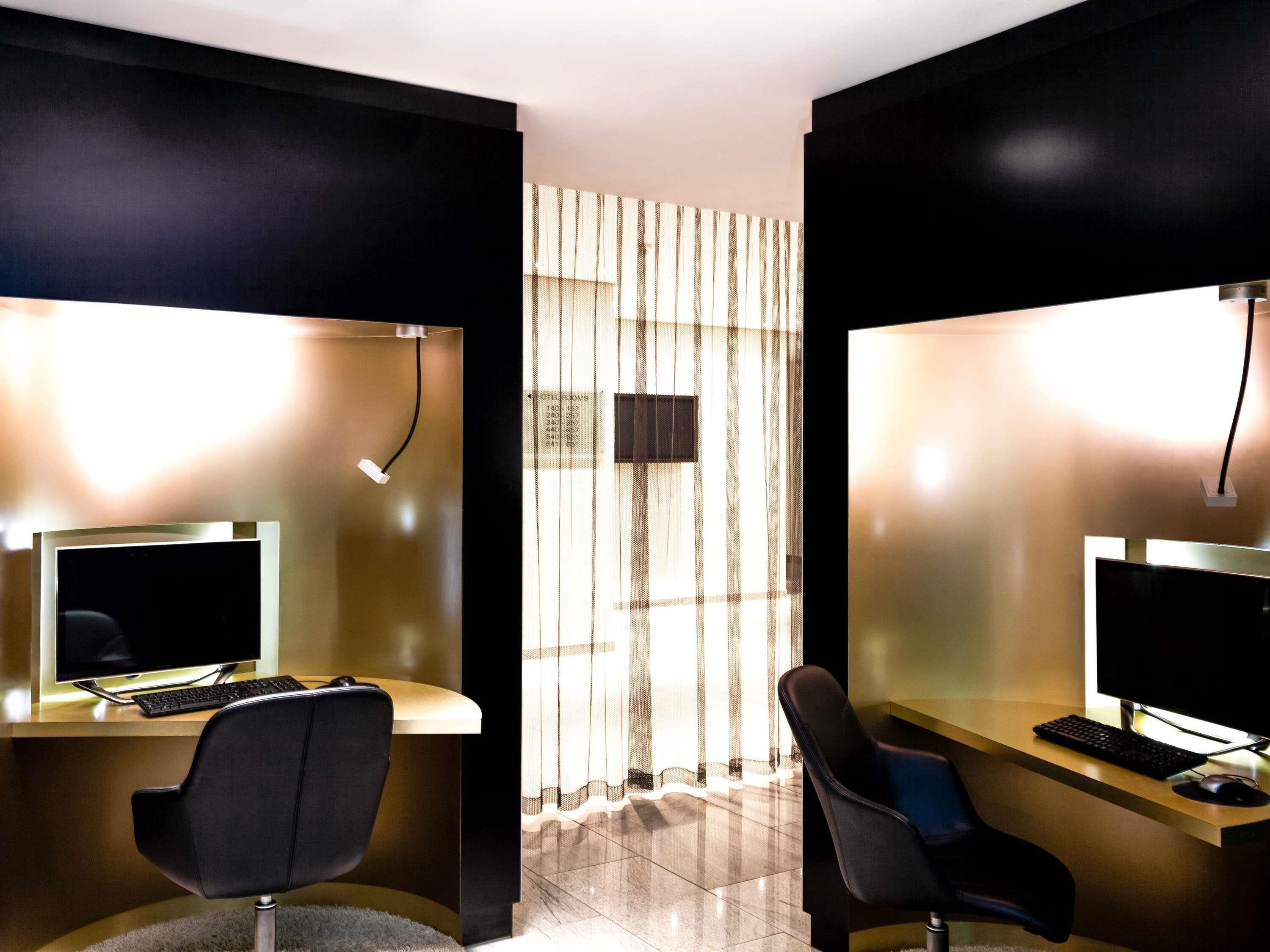 Een hotelkamer met twee bureaus, elk voorzien van een computer en toetsenbord, en een stoel.