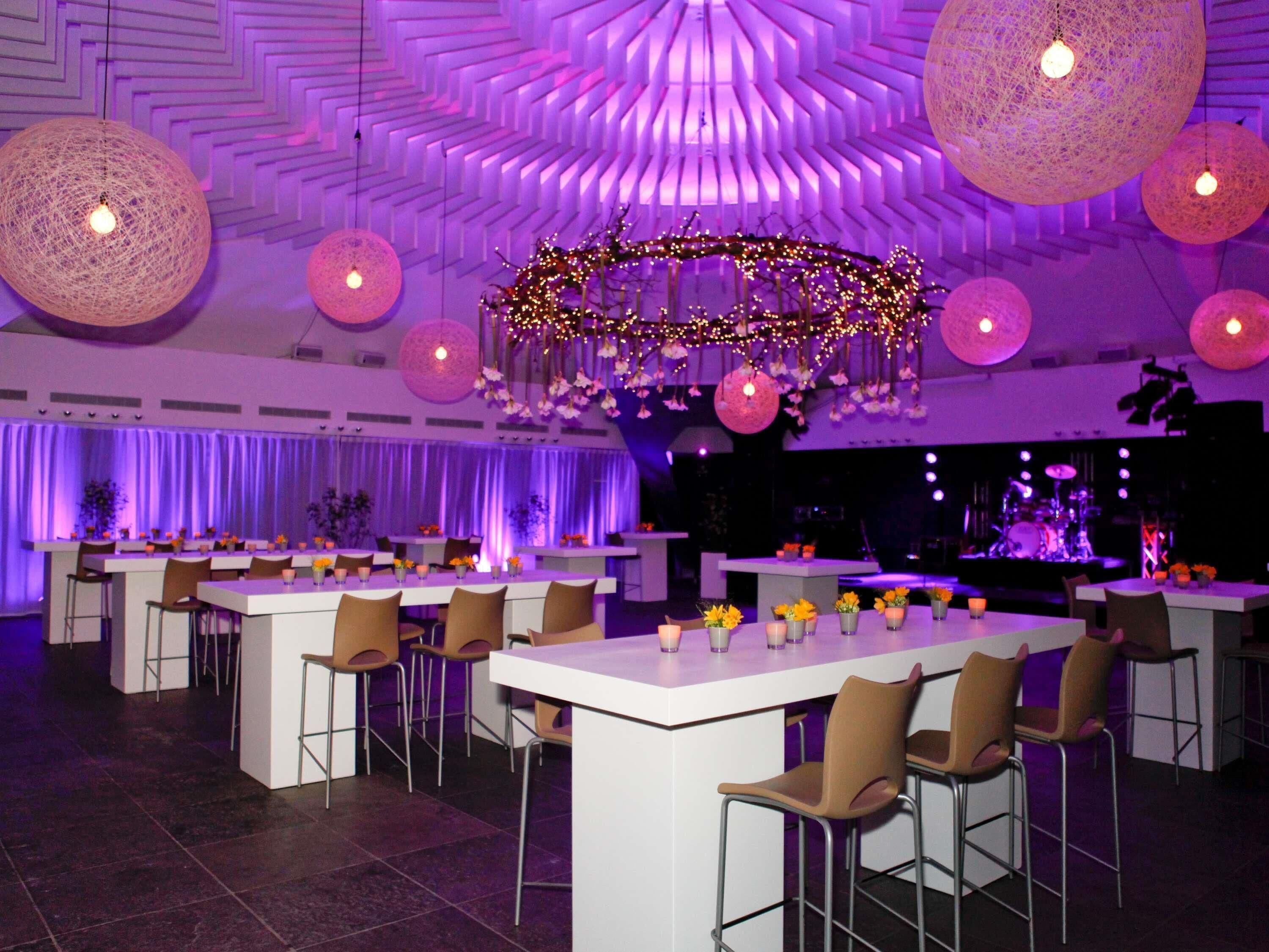 Un ristorante con diversi tavoli, sedie e un palco con strumenti musicali.