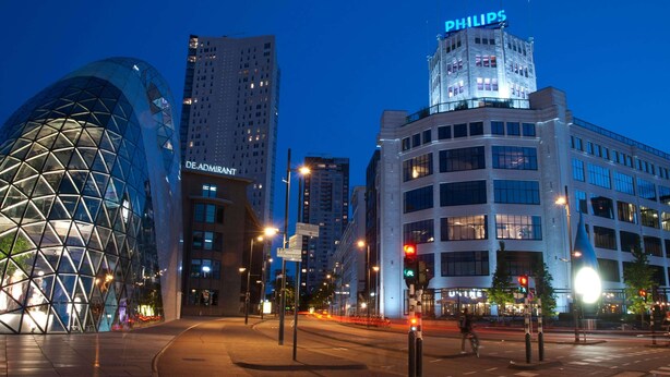 Eine Stadtansicht mit modernen Gebäuden, darunter ein glockenförmiges Bauwerk und ein Gebäude mit der Beschriftung 'PHILIPS'.