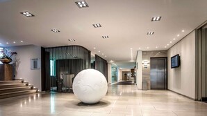 Eine Hotelhalle mit einer großen Globus-Skulptur, einem Empfangsbereich und einer Treppe.