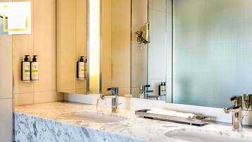 A bathroom with two sinks, a large mirror, and toiletries on the wall.