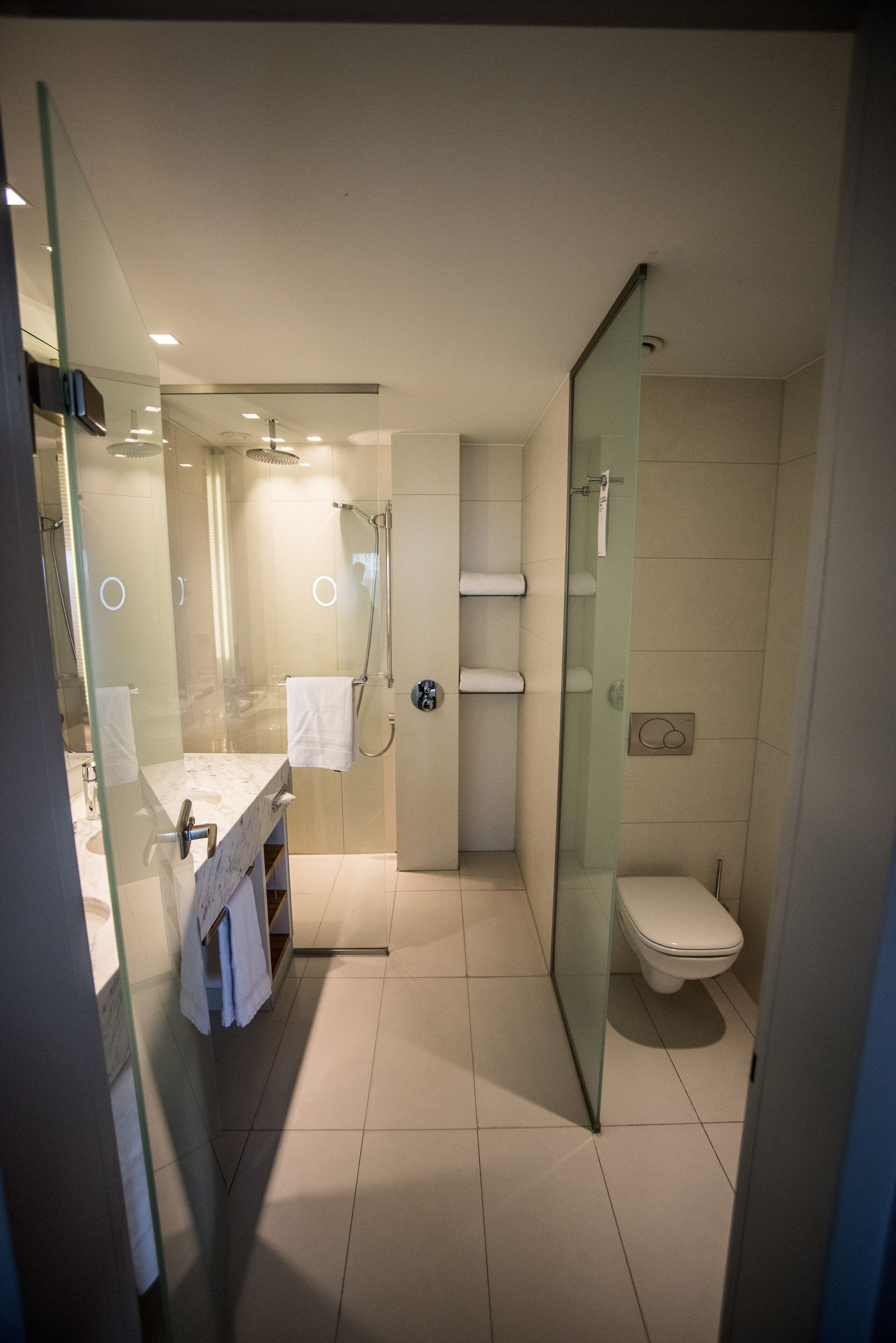 Ein modernes Badezimmer mit Duschkabine aus Glas, Toilette und Waschbecken mit Marmorplatte.