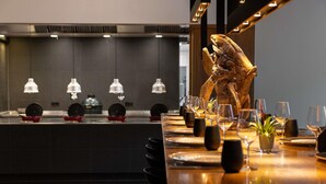 Ein Restaurant mit einem langen Esstisch, der für eine Mahlzeit gedeckt ist, einer dekorativen Holzskulptur und einer Theke mit Küchengeräten.