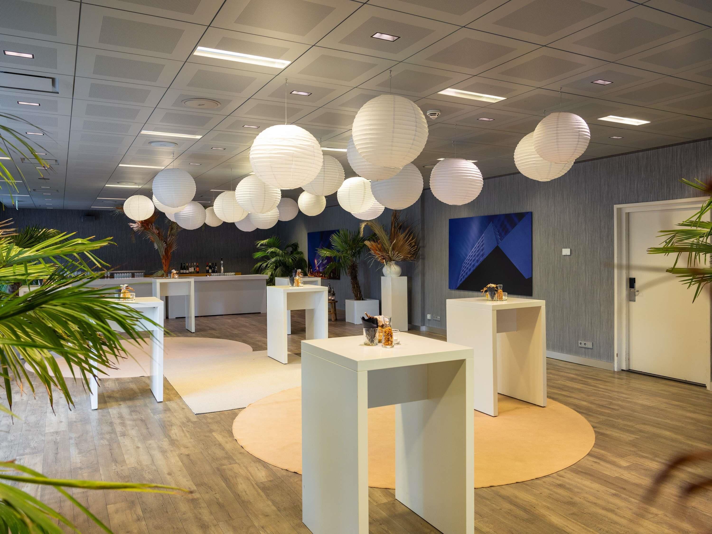 A modern interior with white furniture, hanging paper lanterns, and a wooden floor.